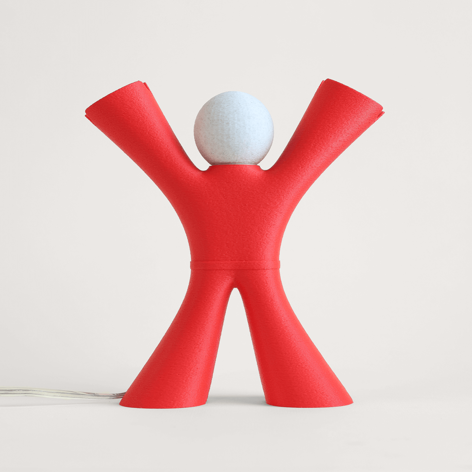 Red lamp shaped like a stylized person with arms outstretched on a light gray background